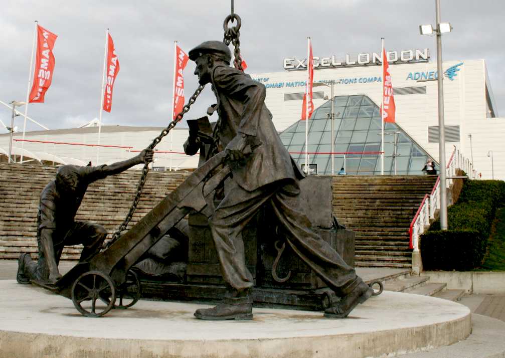 Bronze sculpture men loading cargo manually on a dockside